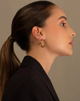 Claudette gold hoop earrings by PIERETTI worn on ear, medium gold hoops for everyday styling, available worldwide