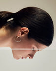 Noele gold wave hoop earrings by PIERETTI, polished 18K gold-plated sculptural design detail