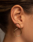 Naty gold drop earrings by PIERETTI worn on ear, sculptural curved earrings for modern styling