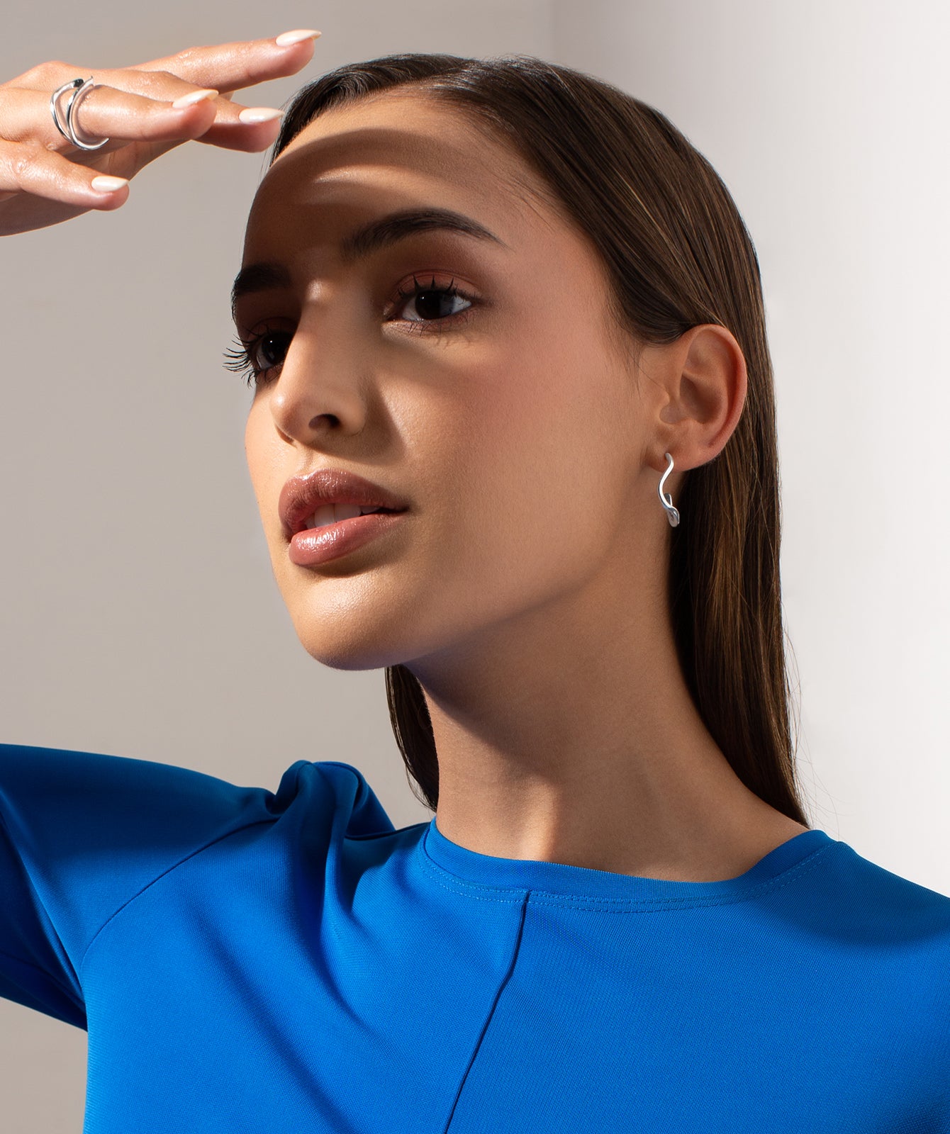 Noele large silver hoop earrings by PIERETTI worn on ear, sculptural wave hoops for modern styling